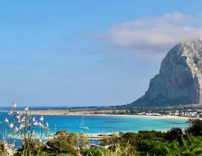 a view of a beach with a mountain in the background at Desy Appartamenti in San Vito lo Capo