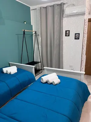 two beds in a blue room with towels on them at LA CASA DI TABBi in Palermo