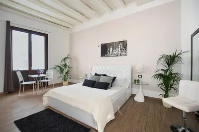 a white bedroom with a white bed and a table at iFlat Dalla Zia Anna in Palermo