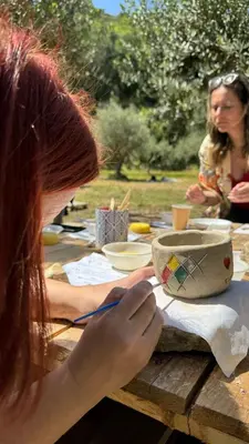 a woman painting a bowl on a picnic table at Elima's Mood in Scopello