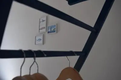 a wooden rack with hangers on a wall with pictures at Elima's Mood in Scopello