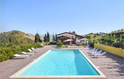 a swimming pool with lounge chairs and a house at Cozy Home In Caccamo With Kitchenette in Caccamo