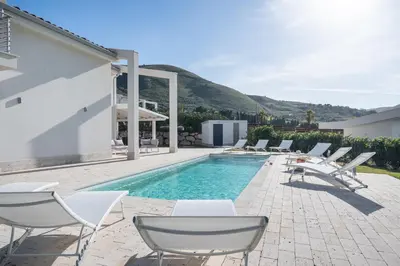 a swimming pool with white chairs and a swimming pool at Villa Costamante con piscina privata in Balata di Baida