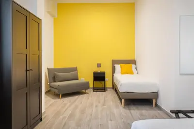 a bedroom with a bed and a chair at Le Cinque Stanze Palermo Room&Breakfast in Palermo