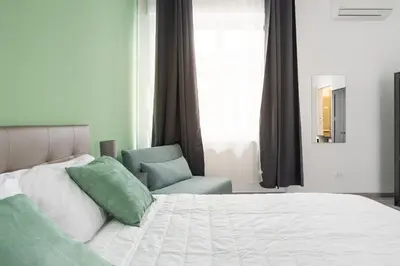 a bedroom with a white bed and a chair at Le Cinque Stanze Palermo Room&Breakfast in Palermo