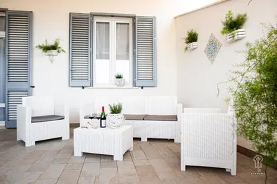a patio with white wicker furniture and a window at Ciatu mè in Alcamo