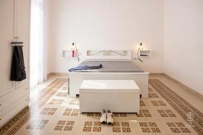 a bedroom with a white bed and a rug at Ciatu mè in Alcamo