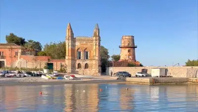 an old building with cars parked next to a body of water at Al Molo 6 in Palermo