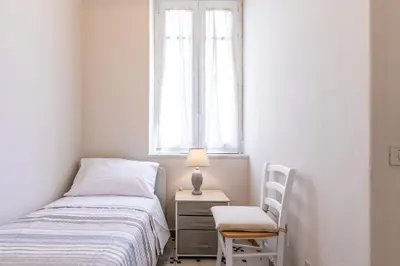 a bedroom with a bed and a chair and a window at GuestHost - Stazione Notarbartolo Bright & Cozy Apartment in Palermo