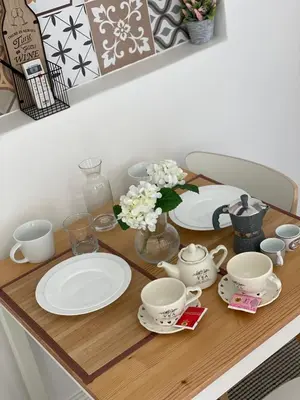 a wooden table with plates and cups and flowers on it at CapoCathedral apartment in Palermo