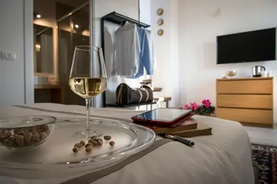 a glass of wine sitting on a bed with a table at Residence Torremuzza - Charming House In The Heart Of Palermo with lovely view in Palermo