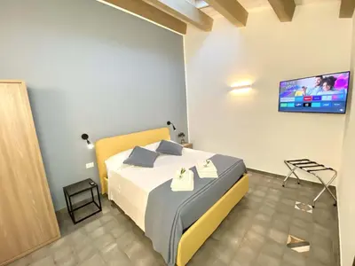 a bedroom with a bed with a tv on the wall at L'Ulivo Comfort Rooms in Terrasini
