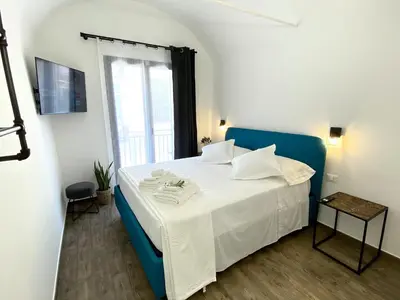 a bedroom with a white bed with a blue chair at L'Ulivo Comfort Rooms in Terrasini