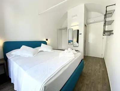 a bedroom with a large white bed with a blue headboard at L'Ulivo Comfort Rooms in Terrasini
