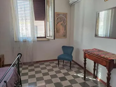 a bedroom with a desk and a blue chair and window at La casa sull'albero in Palermo