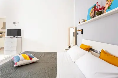 a white bedroom with a bed and a television at La Boucherie in Palermo