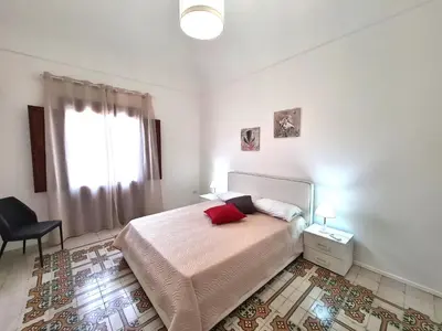a bedroom with a bed and a chair and a window at Casa Lara in Castellammare del Golfo