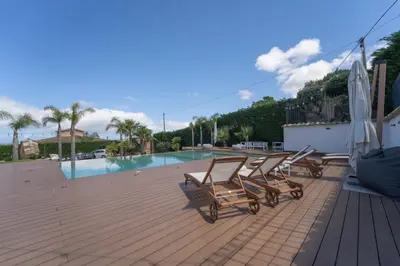 a group of chairs sitting on a deck with a pool at B&b Villa Cusenza in Partinico