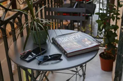 a book and glasses on a table with a potted plant at Sole Apartment in Palermo