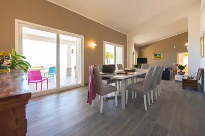 a dining room with a table with chairs and a laptop at La Villa di Sofia in Santa Flavia