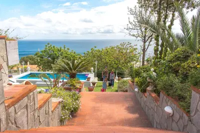 a person walking down a brick walkway near the ocean at La Villa di Sofia in Santa Flavia