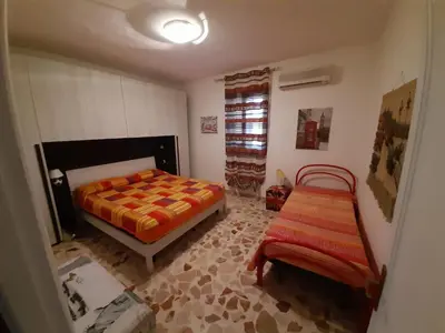 a bedroom with a bed and a chair in it at Villa Noemy in Castellammare del Golfo