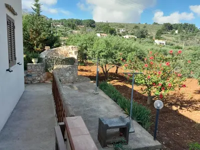 a garden with red flowers and a stone wall at Villa Noemy in Castellammare del Golfo