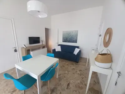 a living room with a white table and blue chairs at Le due conchiglie in Carini