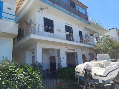 a white house with a boat in front of it at Le due conchiglie in Carini