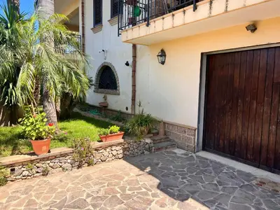 a house with a wooden garage door and a courtyard at IL Rustico di Giò in Carini