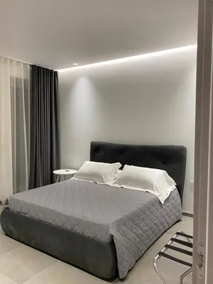 a bedroom with a bed and a white wall at IL DUCA HOUSE e HOLIDAY PRESTIGE in Caccamo