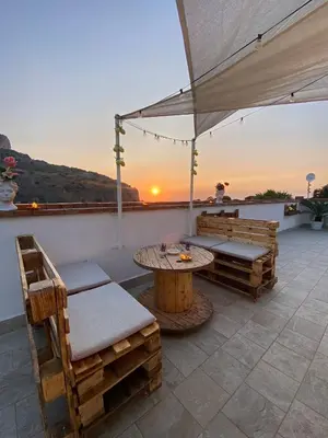 a sunset on a rocky beach with a island in the water at il tramonto in Capaci