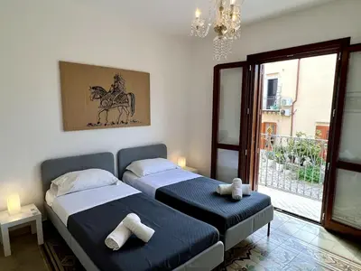 a bedroom with two beds and a window and a chandelier at Castello a Mare in Castellammare del Golfo