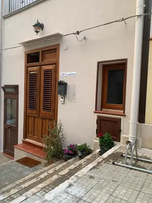 a building with a wooden door and some flowers at Al Vicoletto Boutique in Castellammare del Golfo
