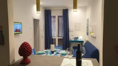 a dining room with a table with a bottle of wine at Mami Holiday House in Castellammare del Golfo