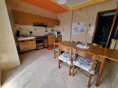 a small kitchen with a wooden table and chairs at Casa di Mamma in Godrano