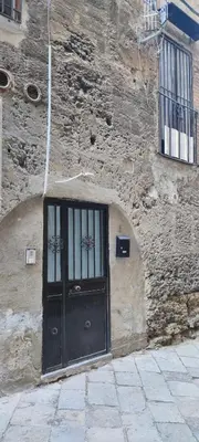 a stone building with a black door on it at Le Casette in Palermo
