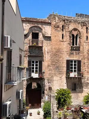 an old brick building with a door and a balcony at Domus Conte Federico in Palermo