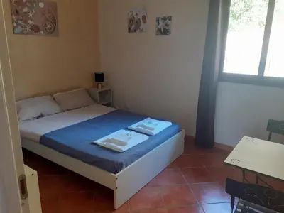 a bedroom with a bed with blue sheets and a window at La Cycas in Trabia