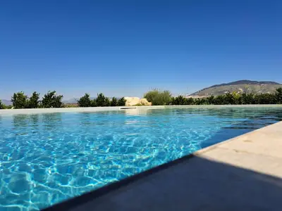 a swimming pool with blue water and trees in the background at Villa Mirò in Castellammare del Golfo