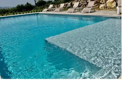 a large pool of blue water with chairs in it at Villa Mirò in Castellammare del Golfo