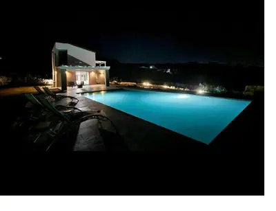 a large swimming pool at night with chairs around it at Villa Mirò in Castellammare del Golfo
