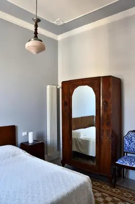 a bedroom with a bed and a mirror and a chair at Battisti 18 Vintage Rooms in Palermo