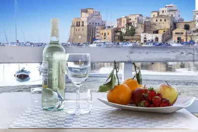 a table with a plate of fruit and a bottle of wine at Hotel Cala Marina in Castellammare del Golfo