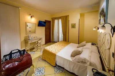 a hotel room with a bed and a desk in it at Hotel Cala Marina in Castellammare del Golfo