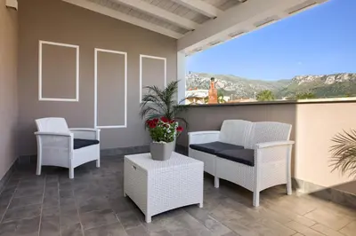 a patio with white chairs and a table and a plant at Le Palme in Terrasini