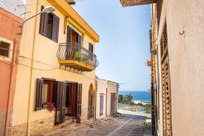 an alley with buildings and the ocean in the background at CIATU ME' Brezza Marina in Castellammare del Golfo