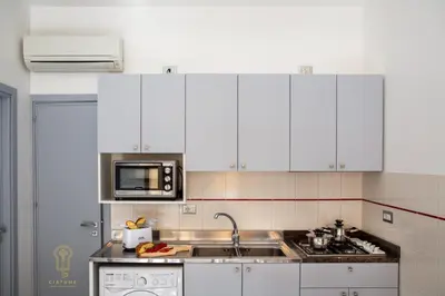 a kitchen with white cabinets and a sink and a microwave at CIATU ME' Brezza Marina in Castellammare del Golfo