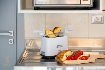 a toaster sitting on a counter with bread and tomatoes at CIATU ME' Brezza Marina in Castellammare del Golfo