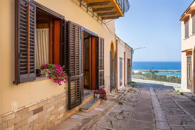 an alley with windows and flowers on a building at CIATU ME' Brezza Marina in Castellammare del Golfo